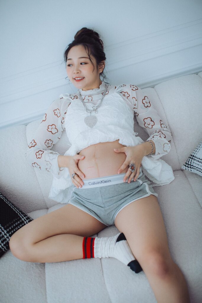 白色沙發上撫著孕肚的孕婦｜婚紗攝影推薦