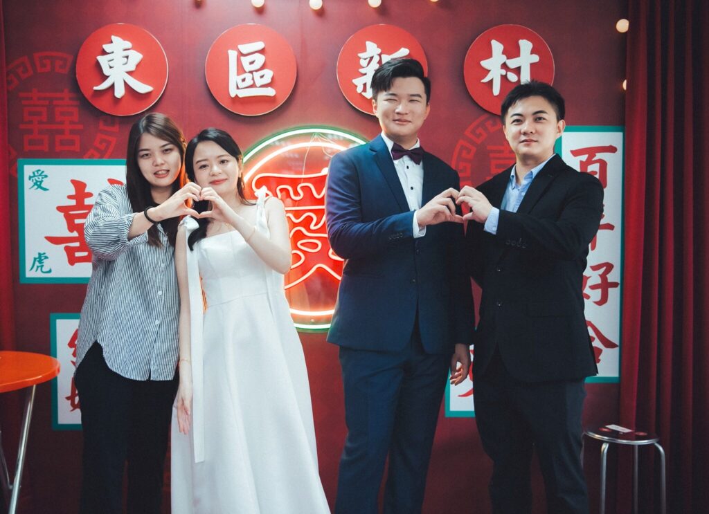 新人與證婚人在東區新村布景前比愛心｜登記結婚紀錄