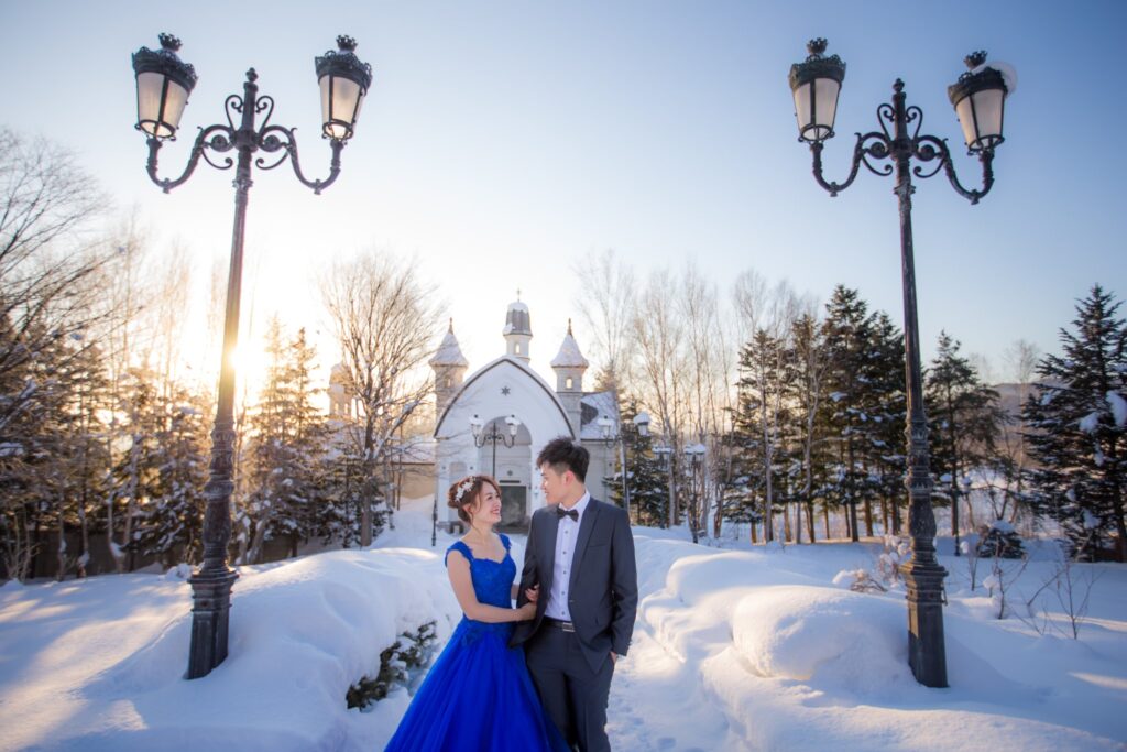 婚紗照姿勢・雪地路燈與白色教堂前 雪地路燈與白色教堂前的新人,新娘穿藍色禮服|婚紗照推薦