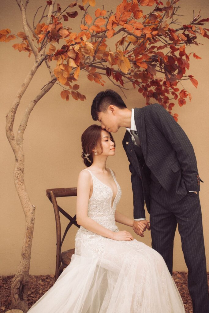 婚紗攝影推薦・乾燥楓葉布景中新郎俯身親吻新娘 乾燥楓葉布景中新郎俯身親吻新娘|婚紗照姿勢
