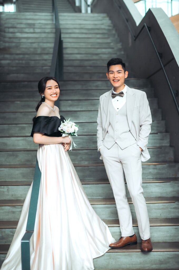 婚紗攝影推薦・樓梯上 樓梯上的新人,新娘穿一字領白紗、新郎白色西裝|婚紗照姿勢