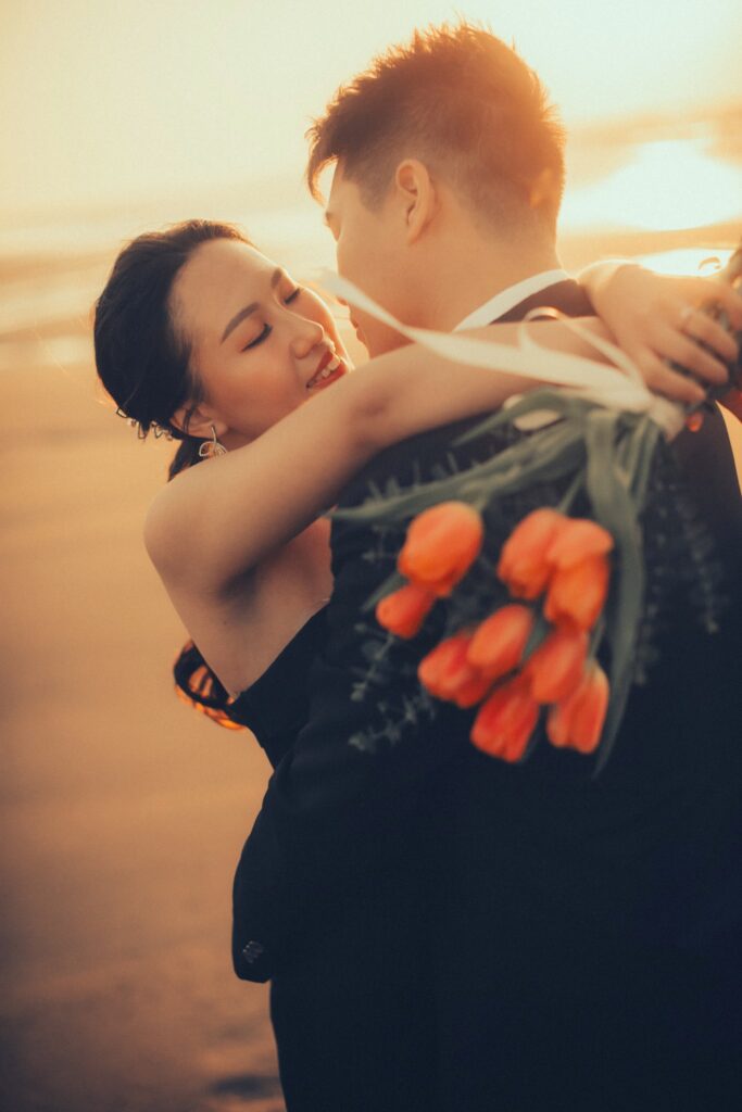 婚紗照姿勢・夕陽下新郎擁抱手捧橘色花束的新娘 夕陽下新郎擁抱手捧橘色花束的新娘|婚紗照推薦