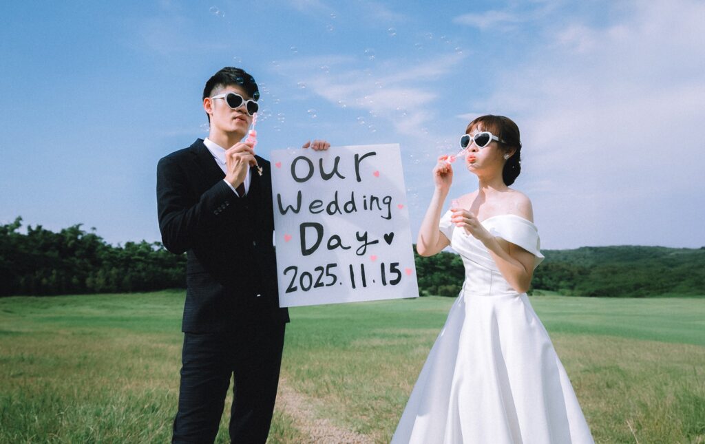 草地上手舉「Our Wedding Day」字卡的新人｜婚紗照推薦