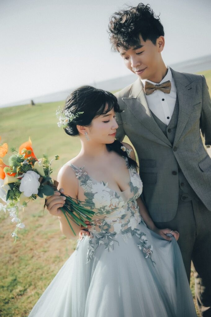 草地上新郎摟著手捧花的新娘｜新竹自助婚紗