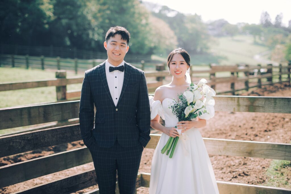 牧場柵欄前手捧花束的新人｜婚紗照姿勢