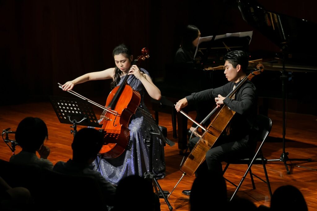 音樂會攝影:雙大提琴合奏 兩位大提琴演奏者在舞台上合奏,後方是鋼琴