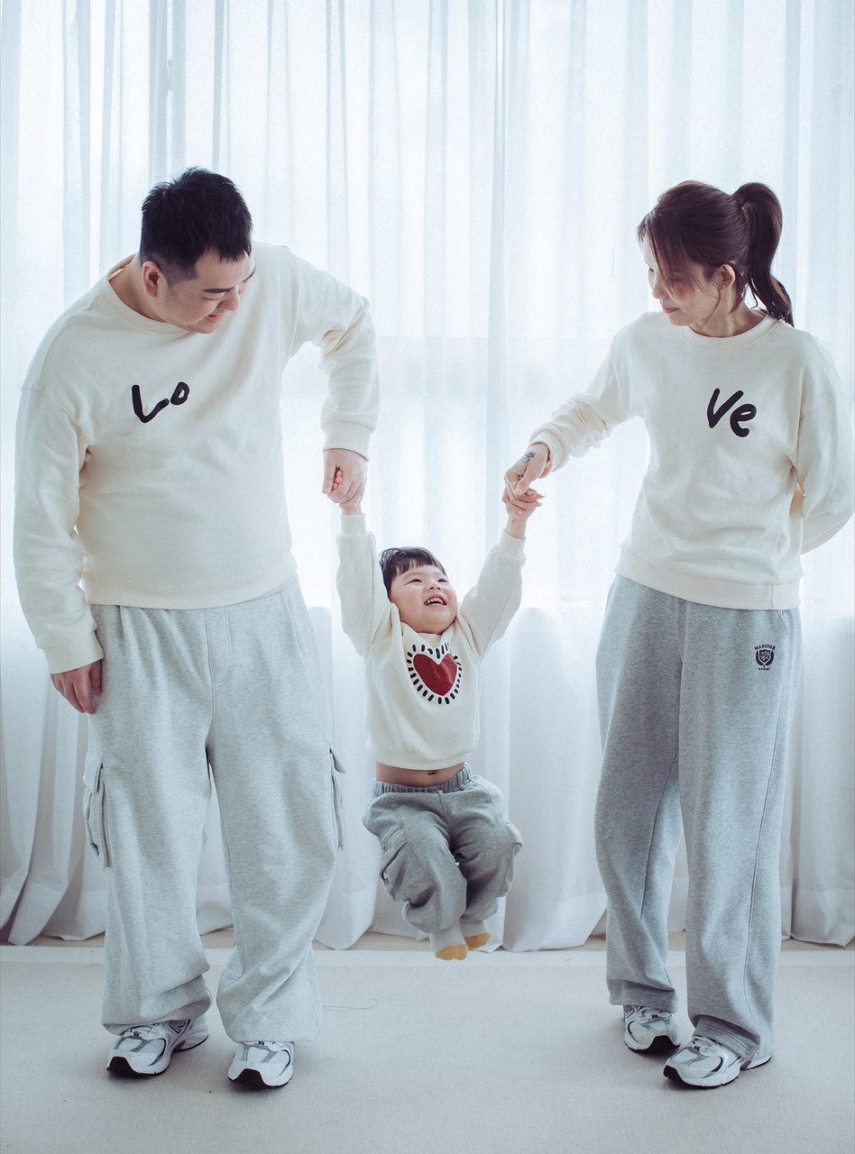 讓孩子做動作,不要叫他不要動 爸爸媽媽牽著小孩的手,三人在白色棚內