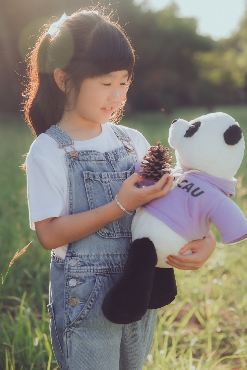 手上給孩子一個喜歡的玩偶,表情更自然 穿吊帶褲的小女孩抱著熊貓娃娃看向鏡頭