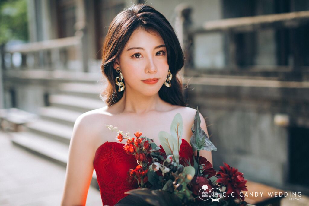 大光圈定焦,背景自然變柔 紅色蕾絲禮服手拿花束的女生半身人像,背景老建築柔和散景
