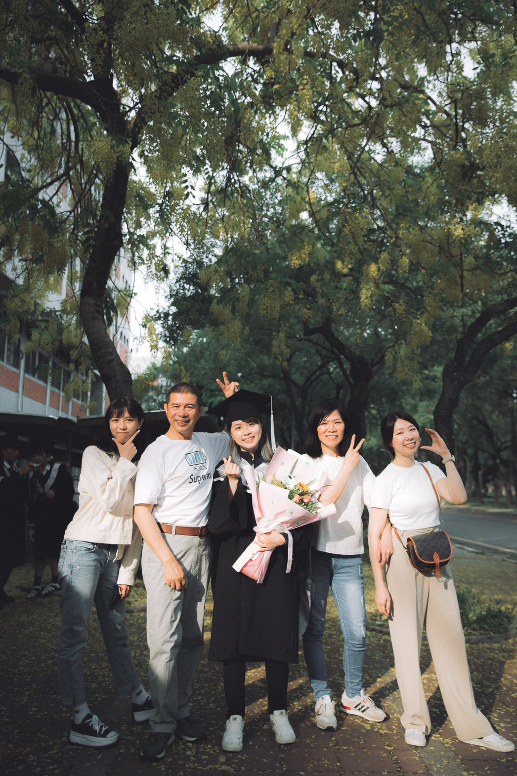 畢業照家人合照:阿勃勒樹下 雲科大畢業照:家人與學士服畢業生在阿勃勒樹下排排站合照