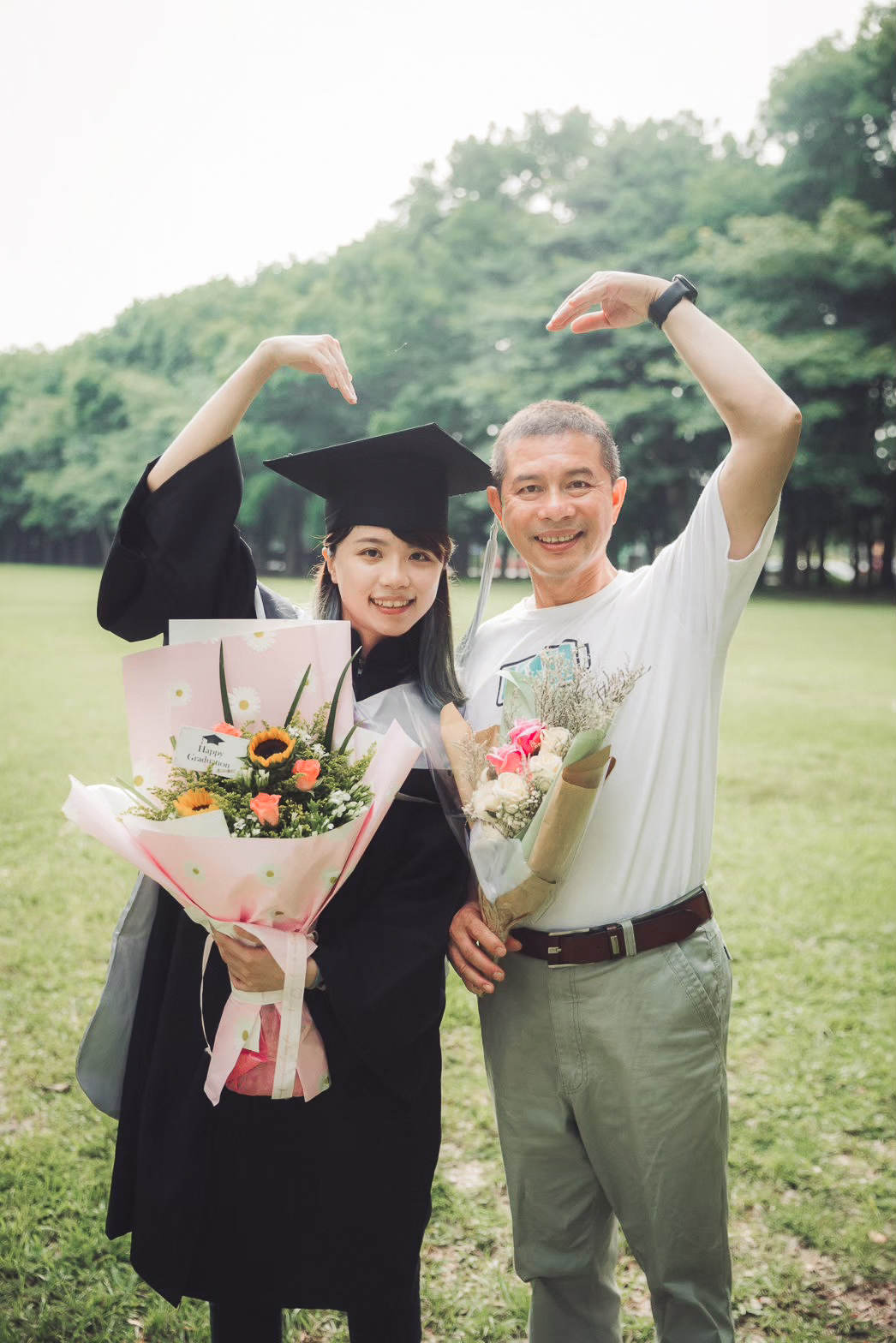 畢業照父女合照:比愛心 畢業照爸爸與女兒在草地上比愛心的父女合照