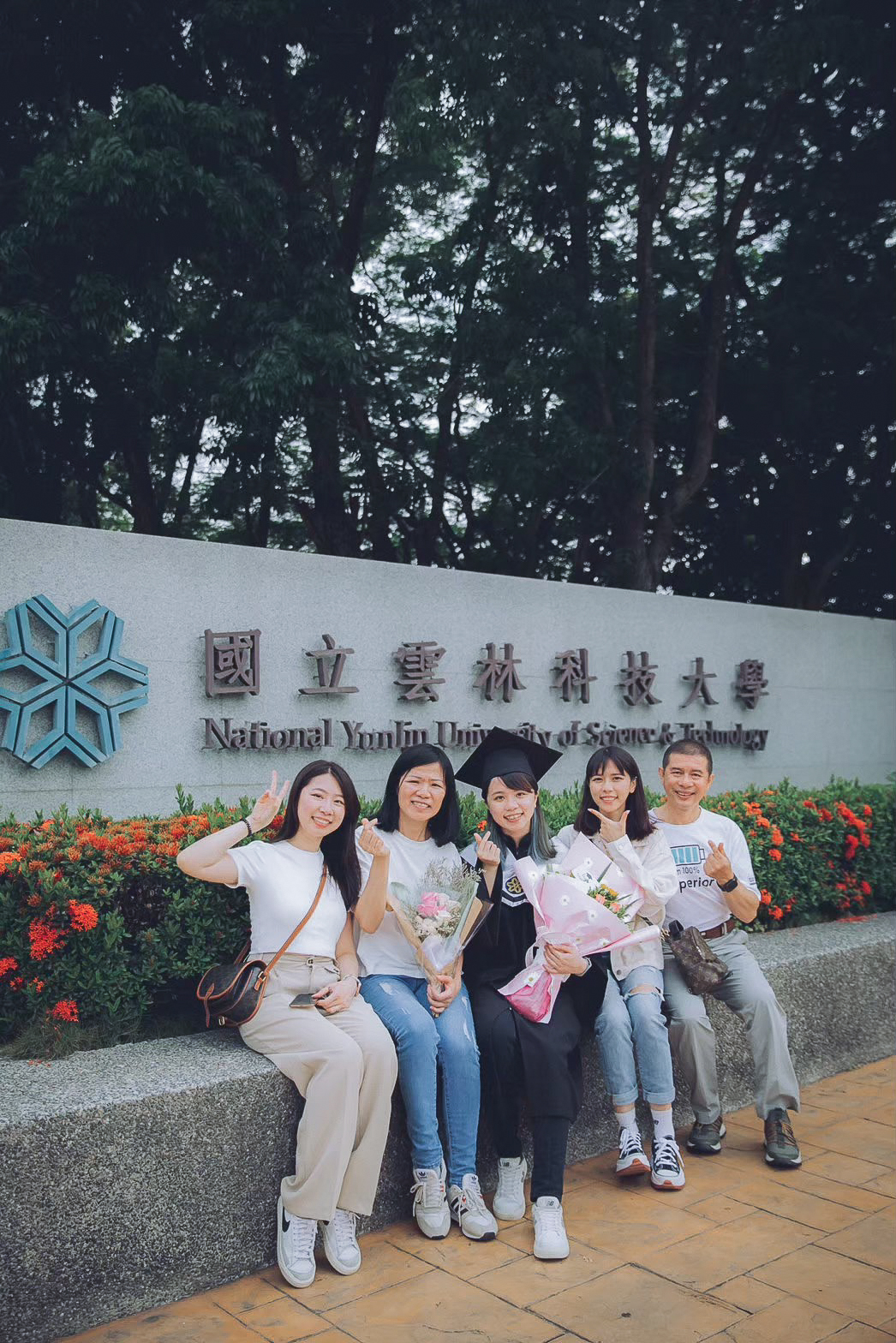 雲科大畢業照:校名石牆前家人合照 雲科大畢業照:國立雲林科技大學校名石牆前,畢業生與家人朋友坐著合照