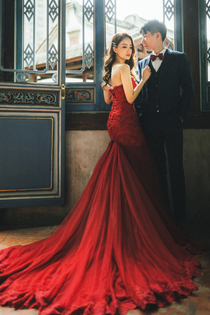 中式婚紗:新人窗邊 中式婚紗:紅色禮服與深色西裝的新人,窗櫺為背景