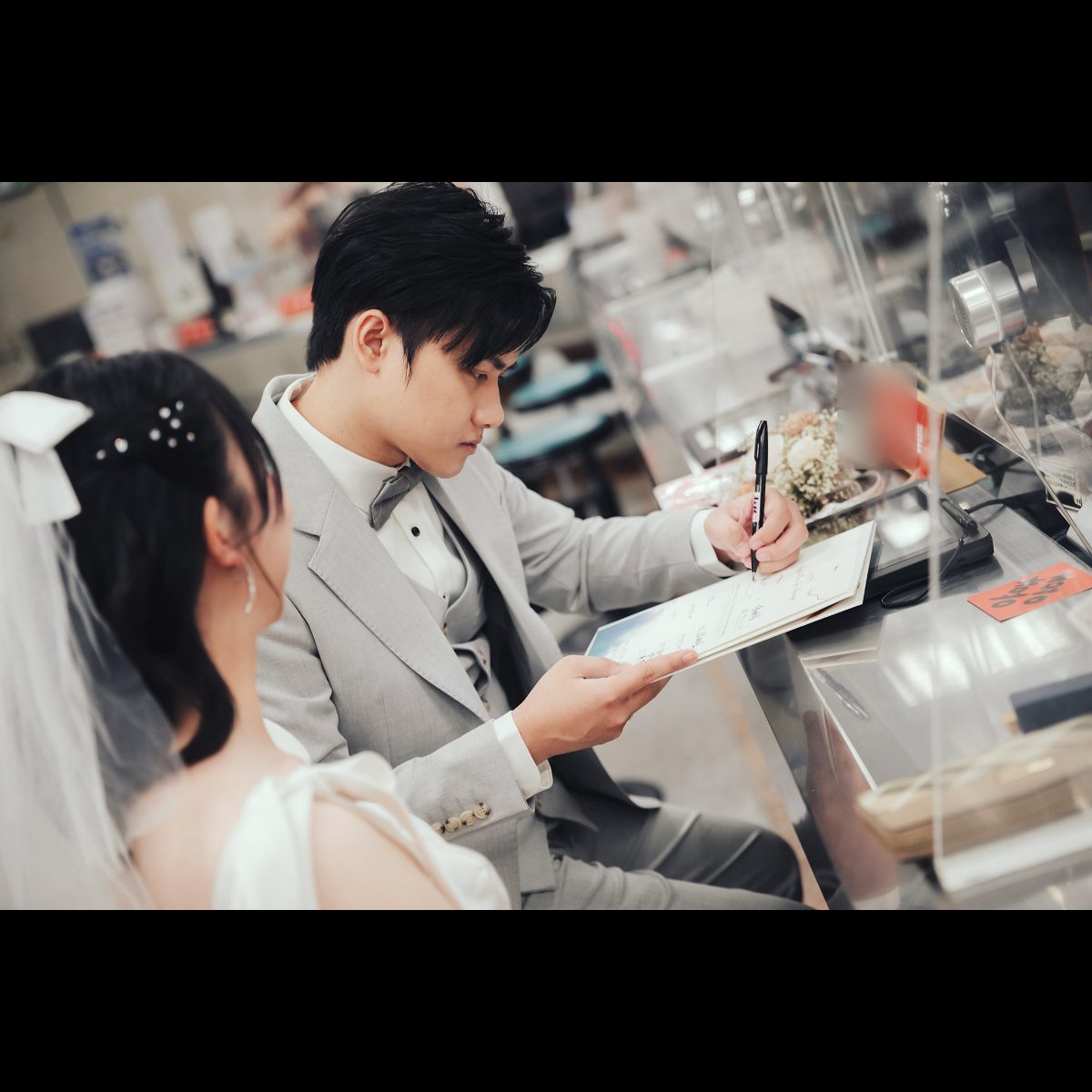 結婚書約簽名|新郎在戶政櫃台簽名 新郎在新竹東區戶政事務所櫃台拿著結婚書約簽名,新娘在旁看
