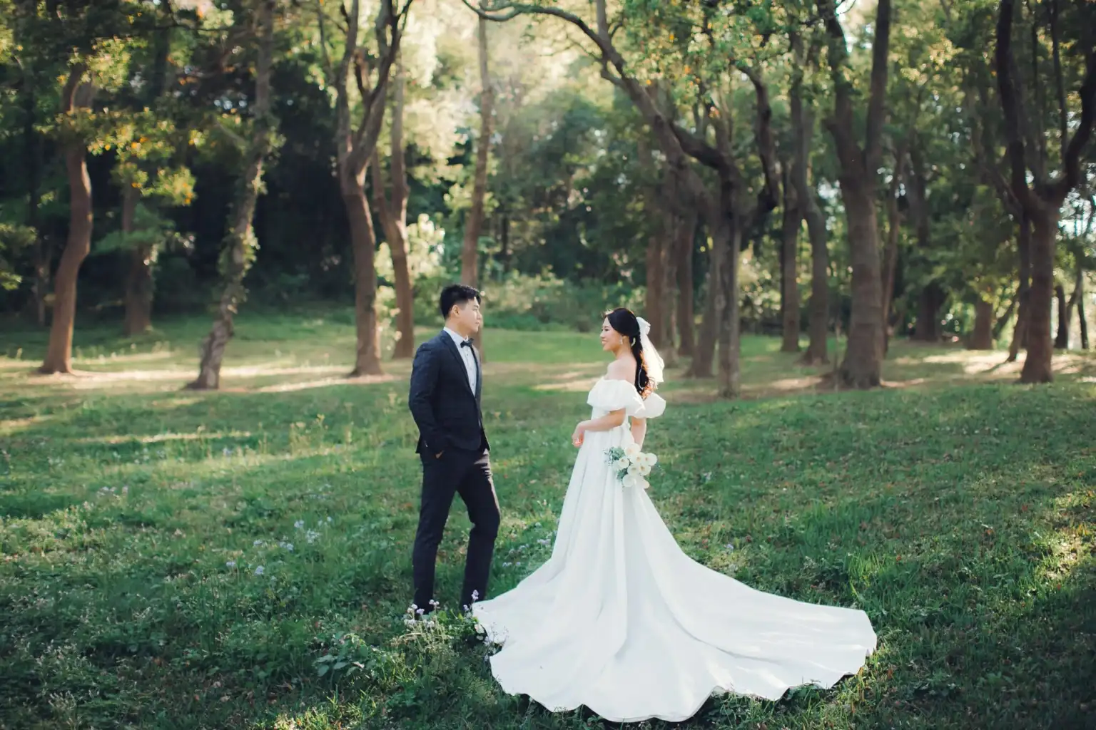新竹森林系婚紗照,新娘穿長拖尾白紗與新郎在陽光樹林草地上對望 新竹森林系婚紗照,新娘穿長拖尾白紗與新郎在陽光樹林草地上對望
