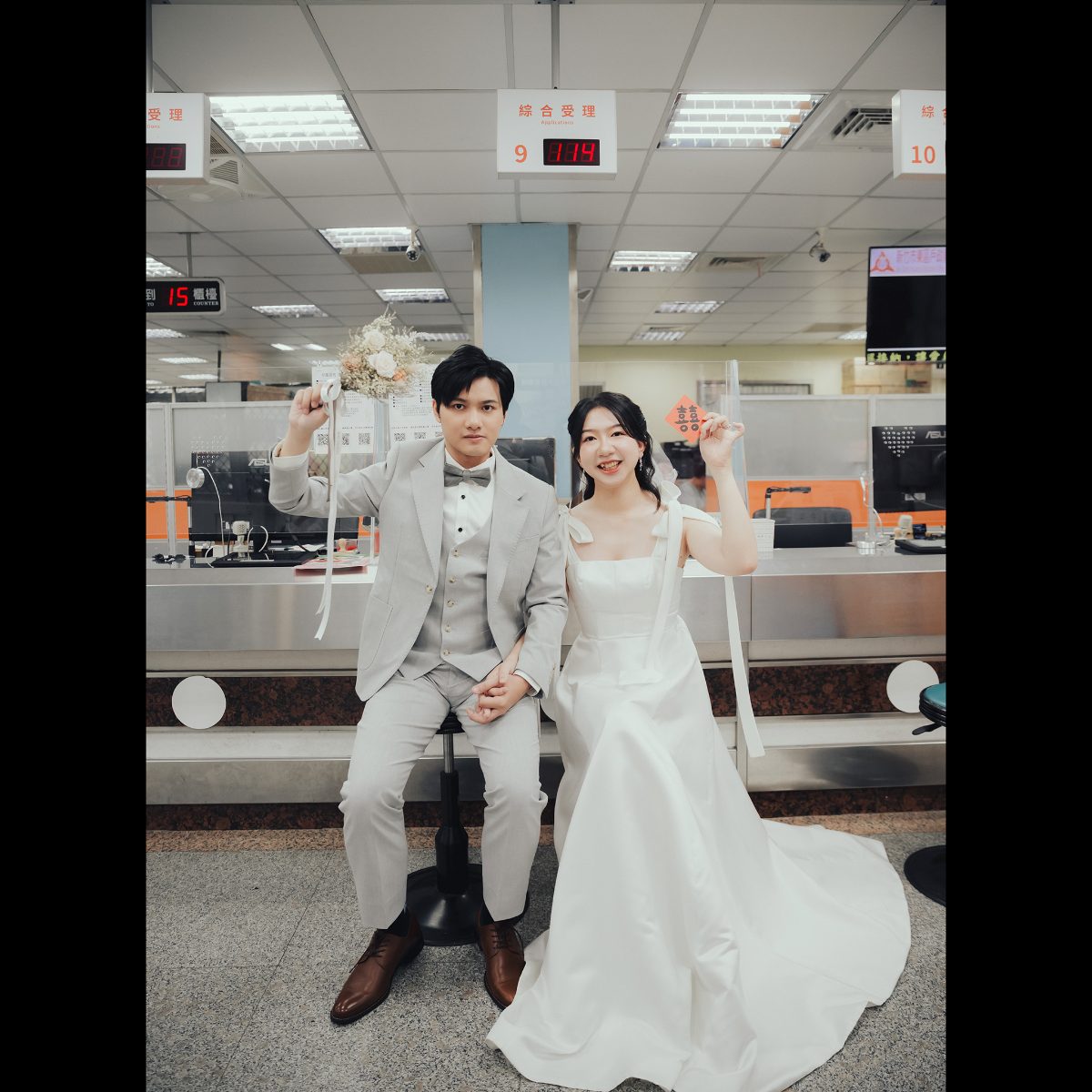 結婚登記照|舉起捧花和囍字 結婚登記照,新郎舉捧花、新娘舉囍字,坐在東區戶政綜合受理櫃台前