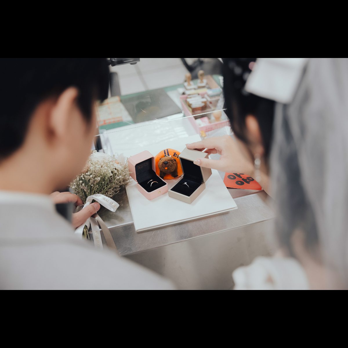 登記結婚戒指|櫃台上的對戒特寫 登記結婚戒指特寫,戶政事務所櫃台上打開的對戒盒與捧花