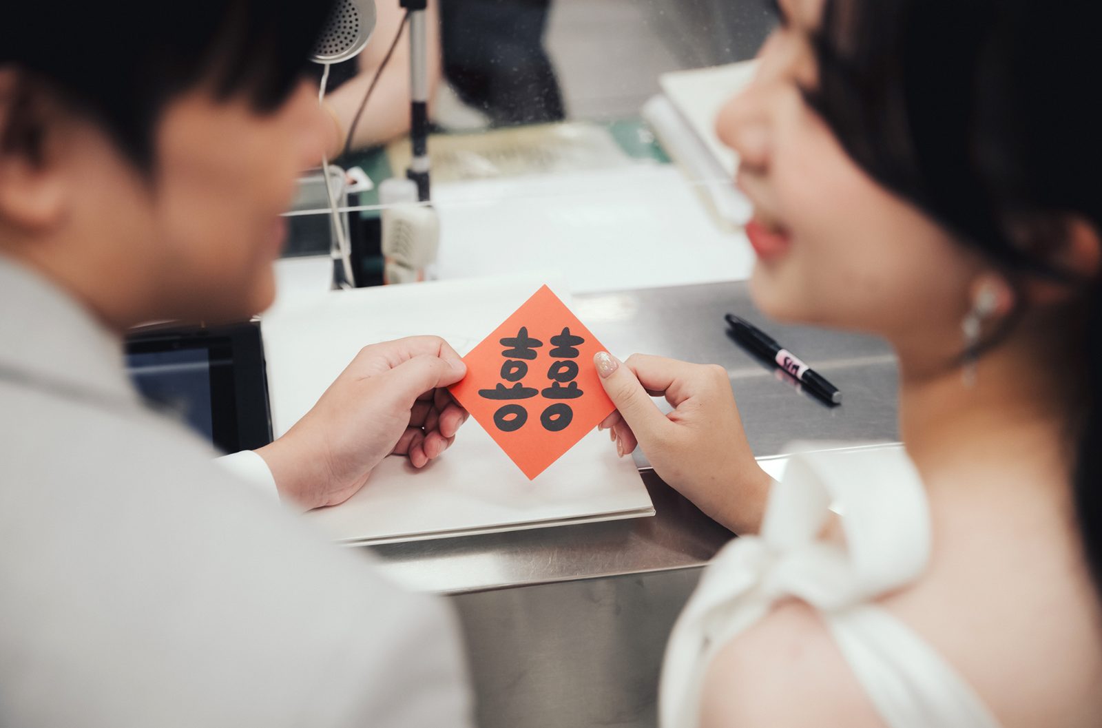 新人在櫃台一起拿著紅色囍字卡|登記寫真細節